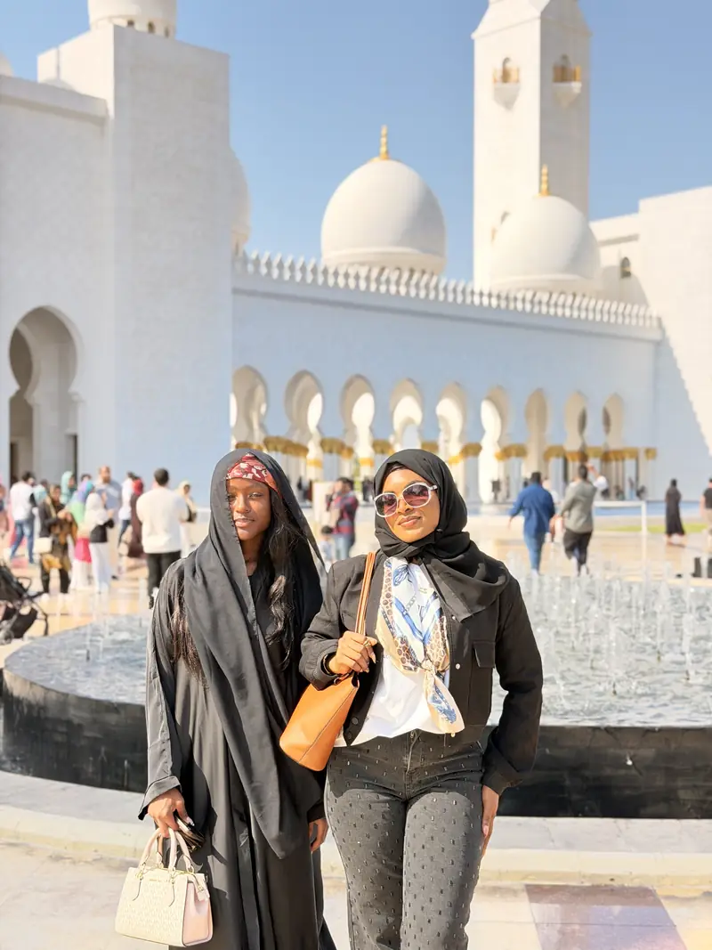 Two women in headscarves in the white marble courtyard of the Sheikh Zayed Grand Mosque
