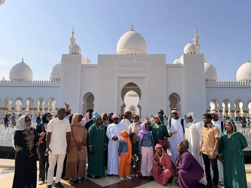 The Myma Travels group in abayas and kanduras in front of the Sheikh Zayed Grand Mosque