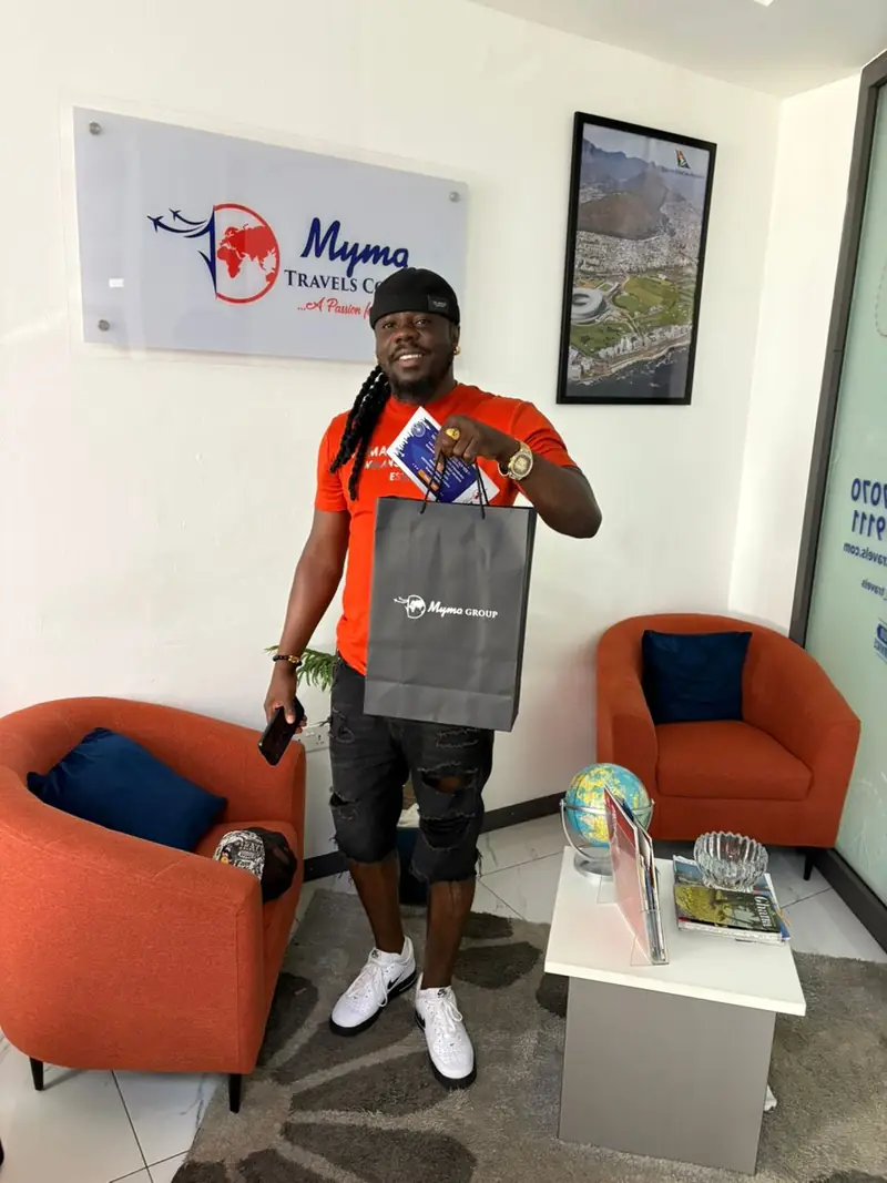 A smiling client holding a Myma Travels gift bag in the Myma Travels office