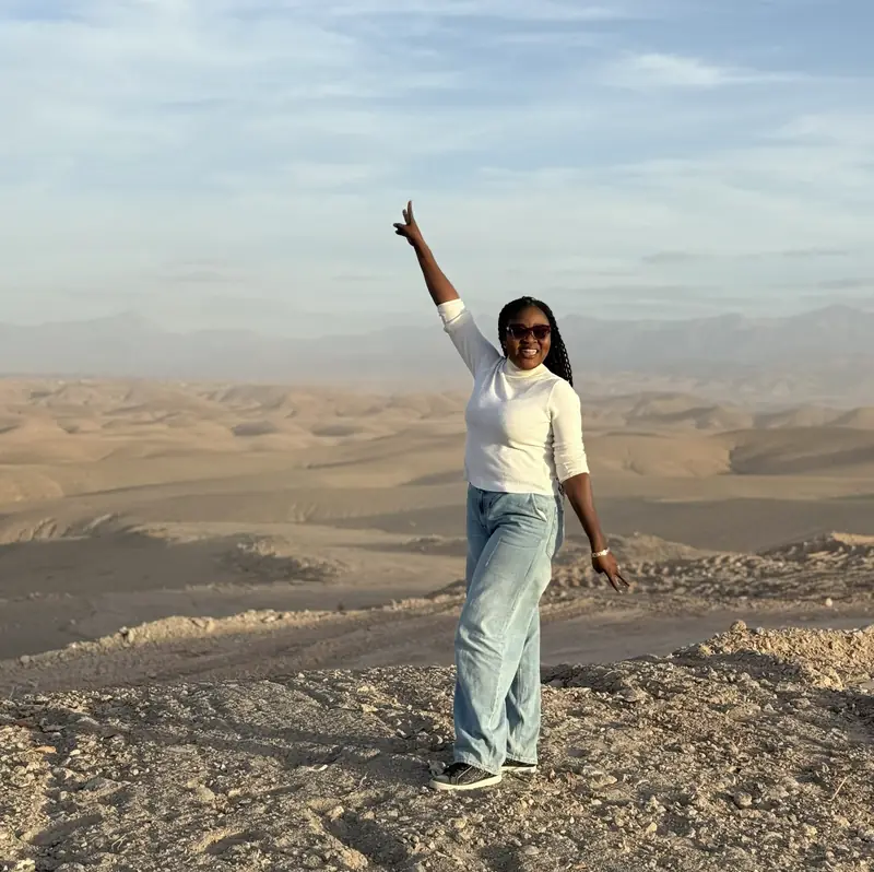 A traveller waving from a hilltop above the stony Agafay desert near Marrakech