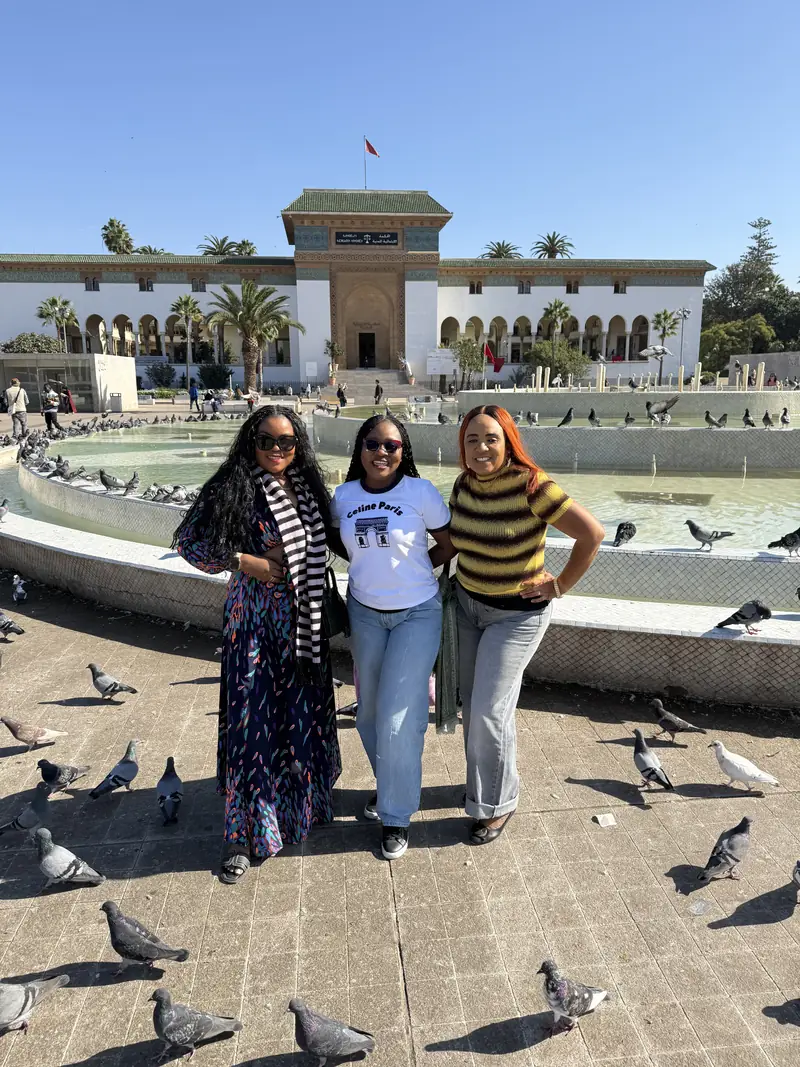 Three travellers standing among pigeons at Mohammed V Square in Casablanca