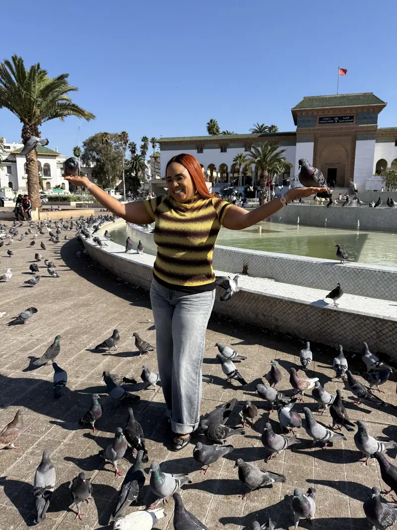 A traveller with arms outstretched as pigeons gather around her in Casablanca