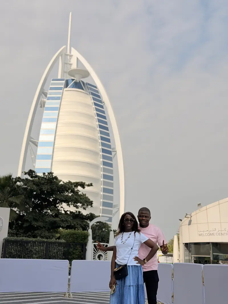 A couple standing in front of the sail-shaped Burj Al Arab hotel