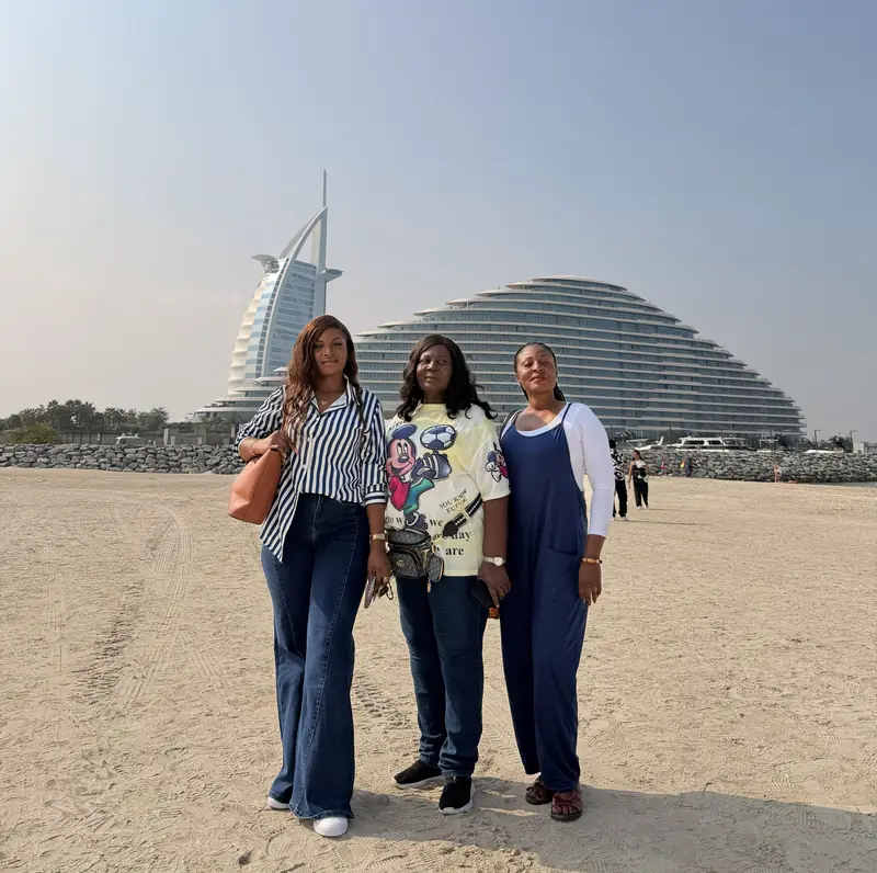 Three travellers on a sandy beach with the Burj Al Arab in the distance