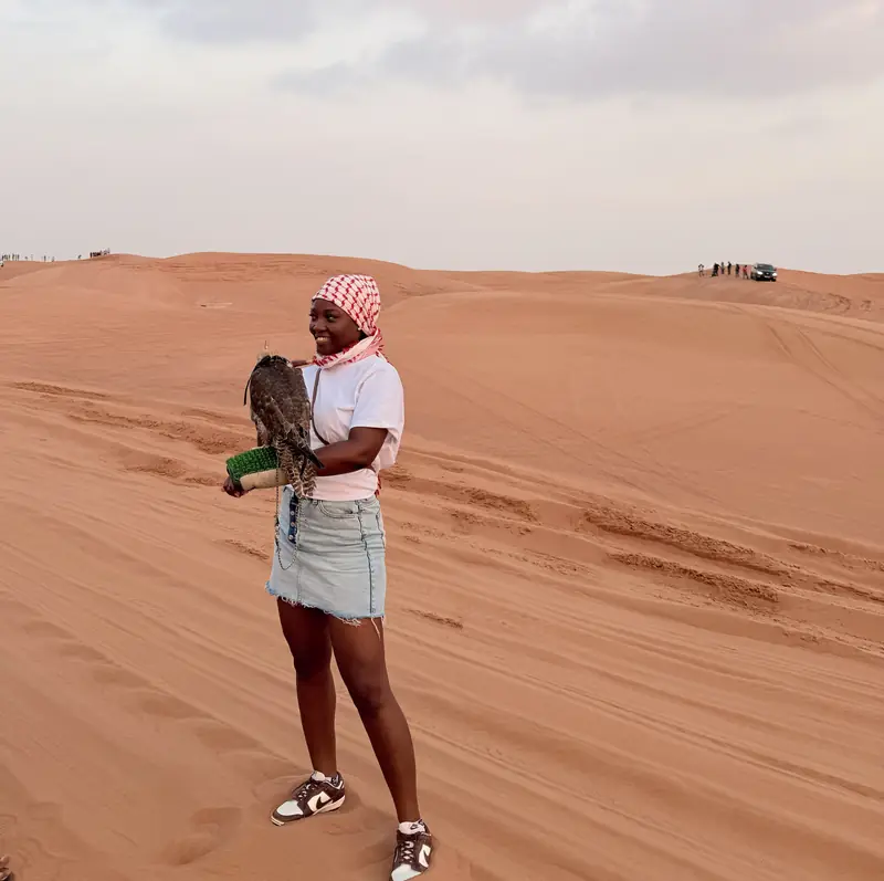 A traveller holding a falcon on her arm in the Dubai desert