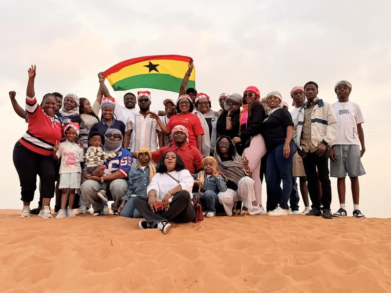 The Myma Travels group on a sand dune holding up a Ghana flag