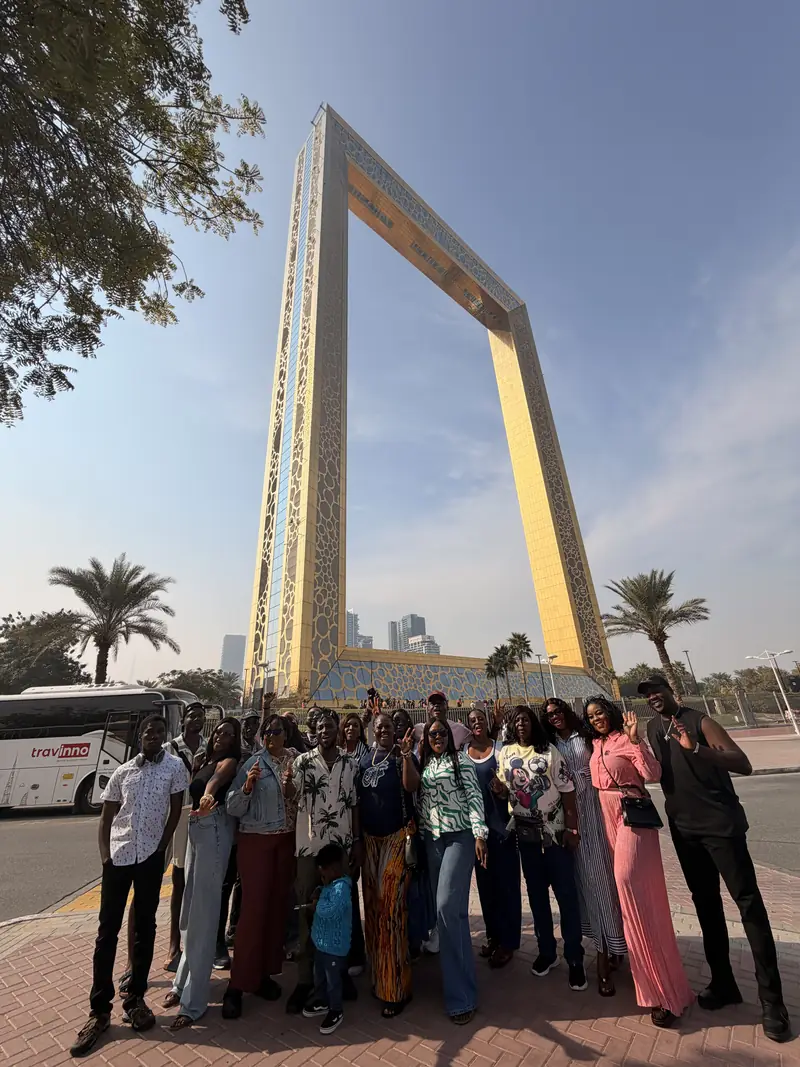 A wide view of the Myma Travels group with the full height of the Dubai Frame behind them