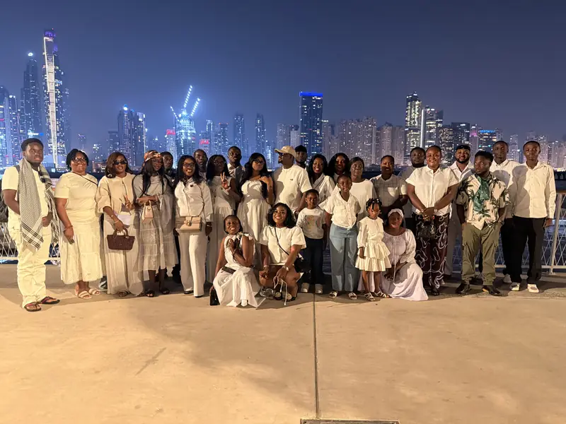The group in white outfits posing against the lit-up Dubai skyline