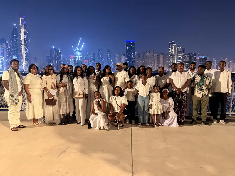 The Myma Travels group dressed in white in front of the Dubai skyline at night