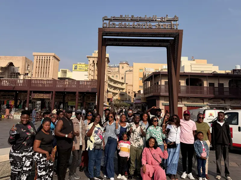 A large Myma Travels group gathered under the Old Baladiya Street gateway in old Dubai