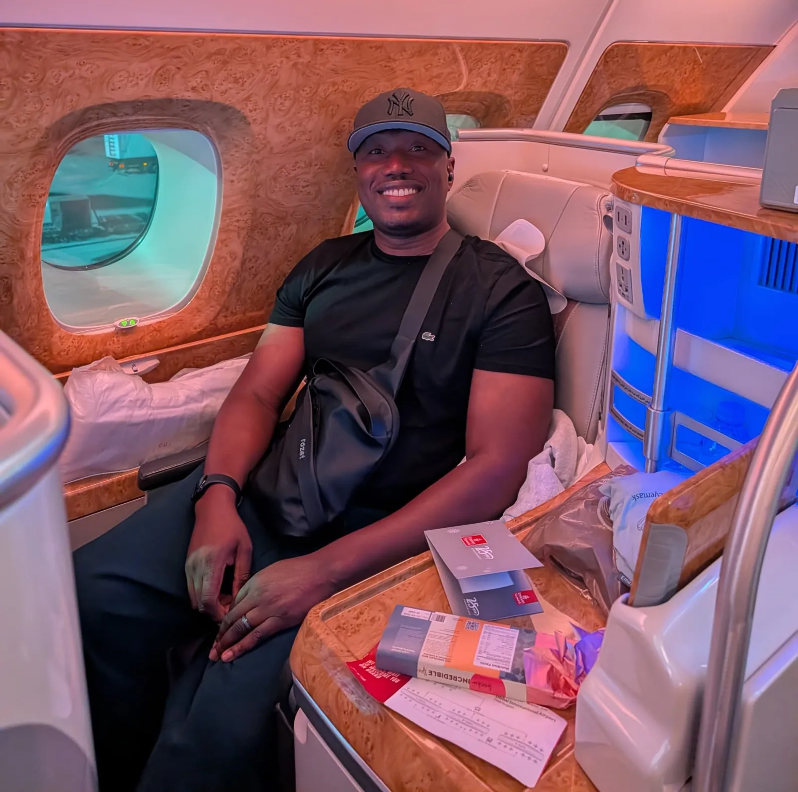 A smiling Myma traveller seated in a private suite on an Emirates flight