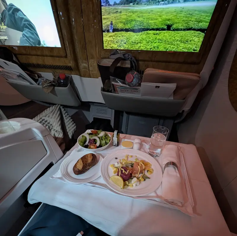 An inflight meal with salad, bread and a main course on a linen-covered table