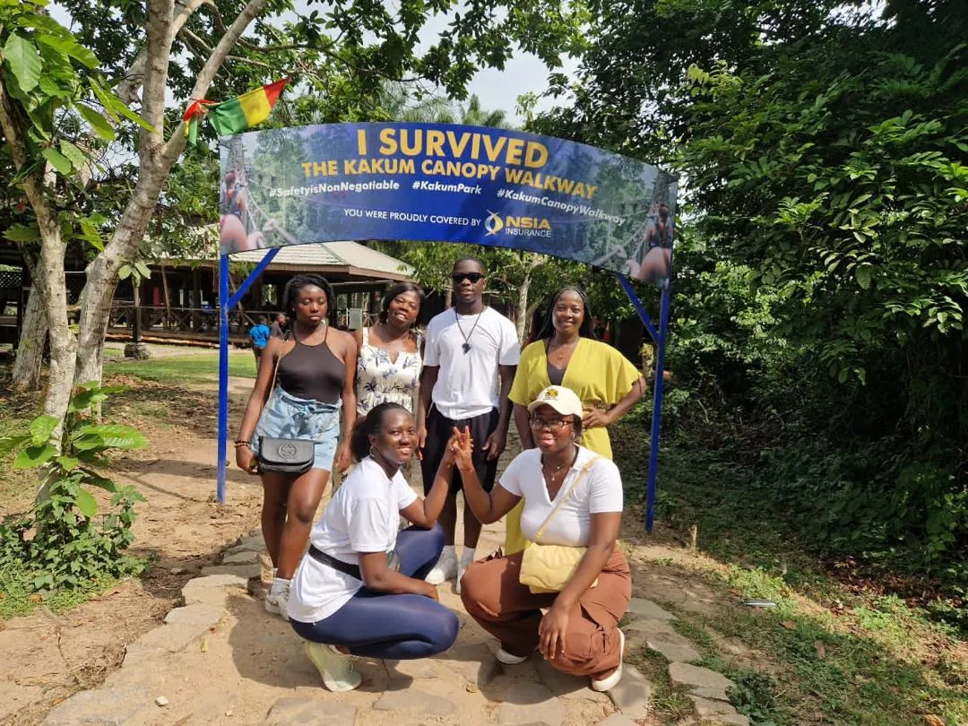 A Myma group under the I Survived the Kakum Canopy Walkway sign at Kakum National Park