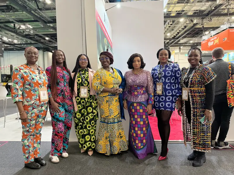 Seven women in African print outfits at a travel trade fair
