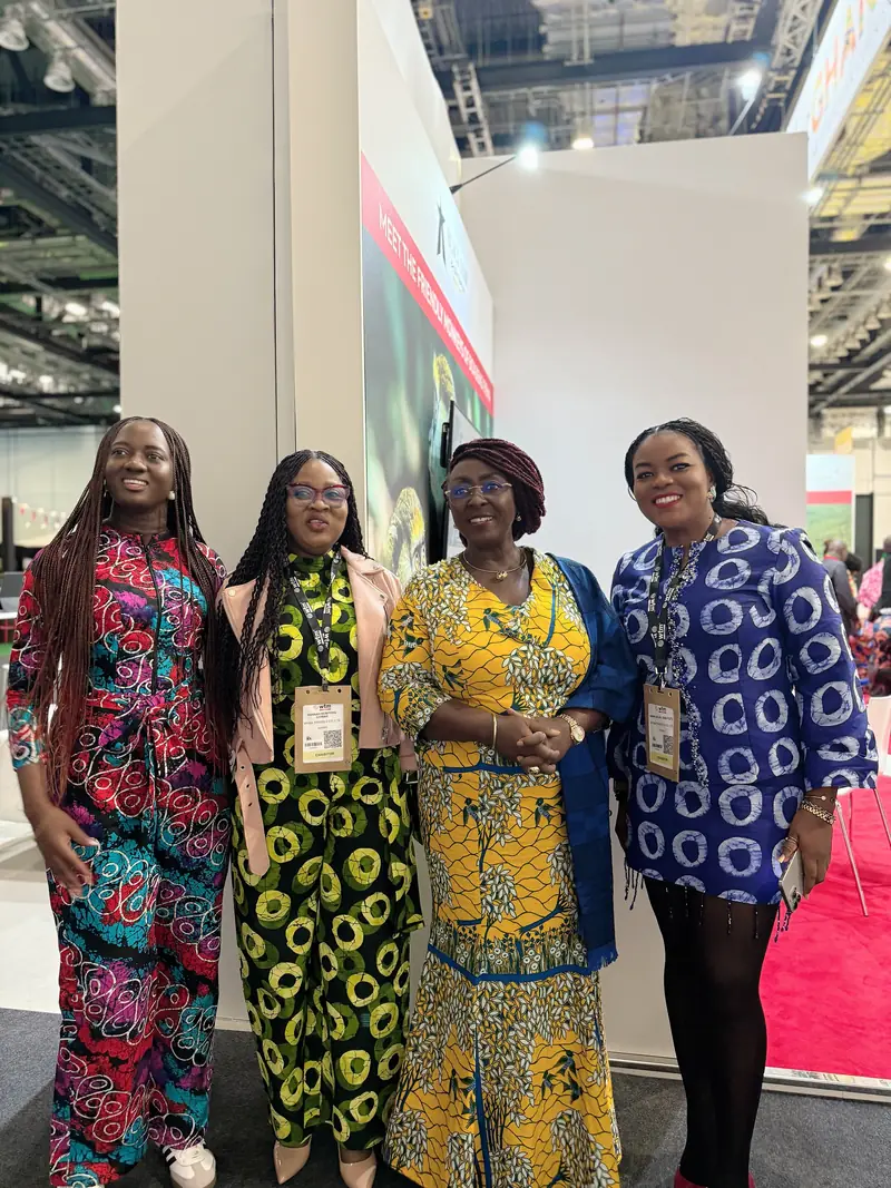 Four women from the Myma Travels team in colourful African print outfits at a trade fair