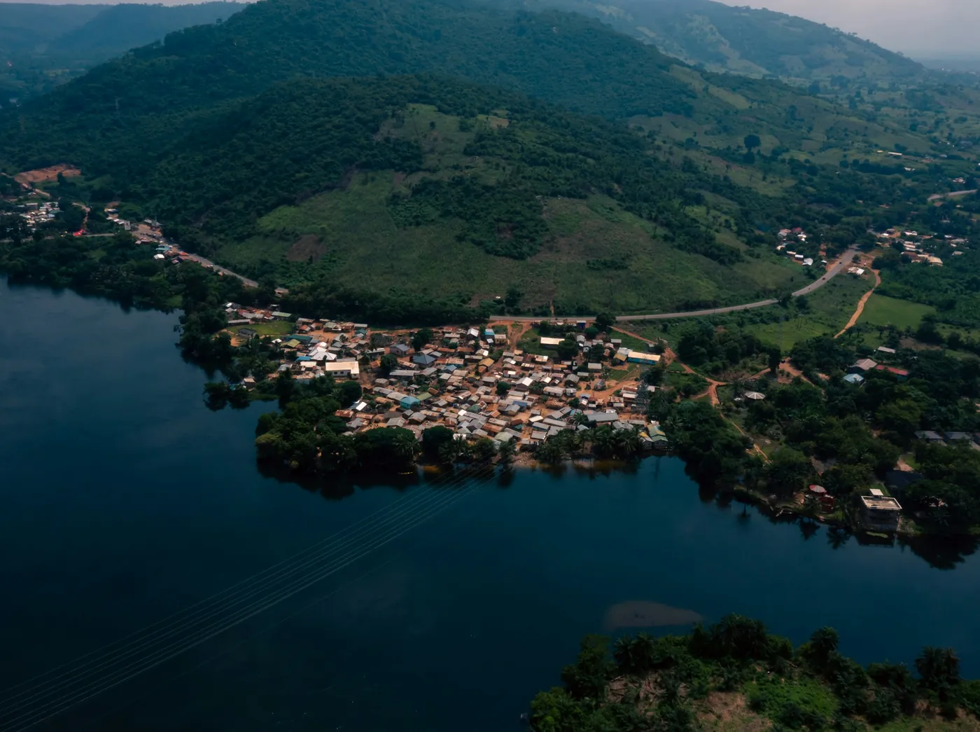 Aerial view of a lakeside town on the Volta Lake at the foot of green hills in Akosombo